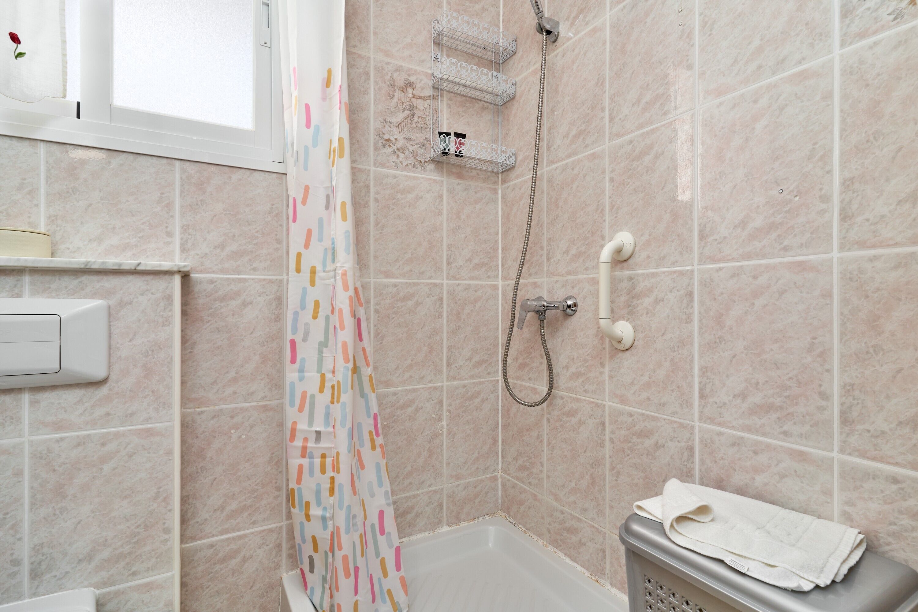 Ein Badezimmer mit Dusche, Toilette und Wäschekorb.