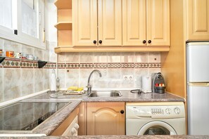 A kitchen with wooden cabinets, a stainless steel sink, a built-in washing machine, and a coffee maker.