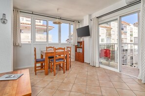 A balcony with a dining area, a television mounted on the wall, and a view of the cityscape.