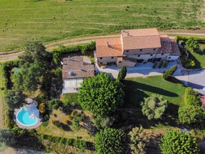 A large house with a tiled roof, a swimming pool, and surrounding greenery.