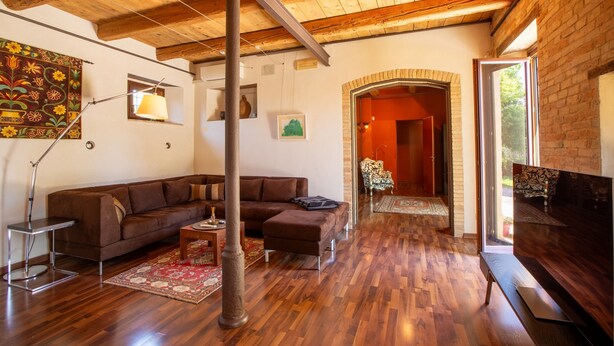 A living room with a wooden ceiling, a brown sectional sofa, a coffee table, a lamp, and a TV. - Villa 'Gelso' with Private Pool, Wi-Fi and Air Conditioning (Belvedere Ostrense)