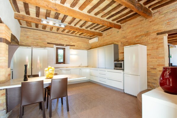 A kitchen with white cabinets, a large island, and a red vase.