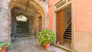 A stone archway leading to a staircase, a potted plant, and a wooden door. - Amazing apartment in Carro with house a panoramic view (Carro)