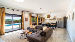 Uma sala de estar moderna com sofá, mesa de centro e vista para uma piscina.