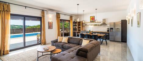 A modern living room with a sofa, coffee table, and a view of a pool.