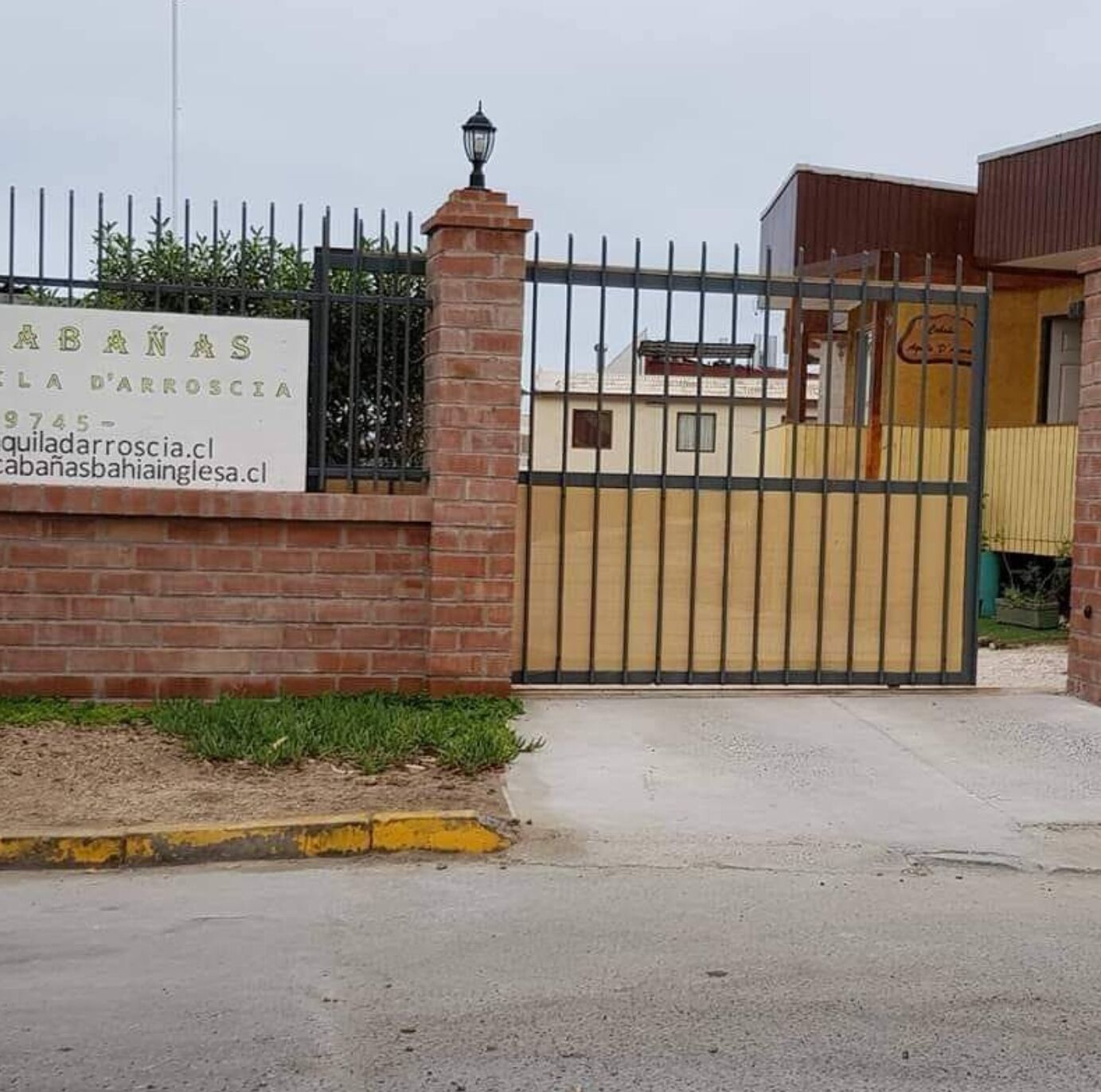 Une entrée fermée par un portail mène à un immeuble sur lequel on peut lire l’inscription « ABANAS FLA D’ARROSIA », ainsi que les coordonnées.