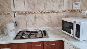 A kitchen with a gas stove, a microwave, and a gas valve sign. - Cabañas Aquila D'Arroscia (Caldera)