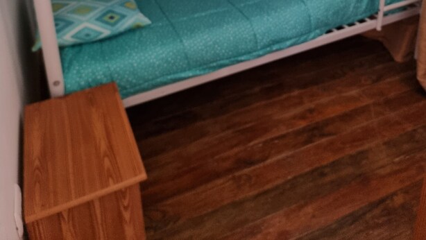 Un lit superposé avec une literie de couleur turquoise et une table de chevet en bois.