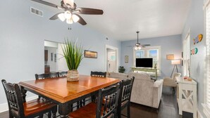 A dining area with a wooden table and chairs, a ceiling fan, and a plant centerpiece. - Family-friendly, centrally located beach house. 1 block from the Seawall! (Galveston)