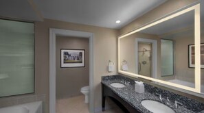 Features a double sink vanity, granite countertop, and frameless mirror with integrated lighting.
