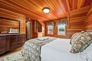 A bedroom with wooden paneling, a bed with floral bedding, a dresser, and a window with curtains.