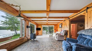 Eine Holzhütte mit Steinboden, einer Couch, einem Tisch und einem Kamin.