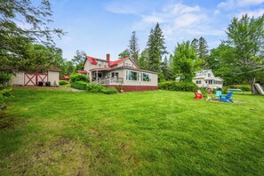 A house with a red roof, a covered porch, and a well-maintained lawn.