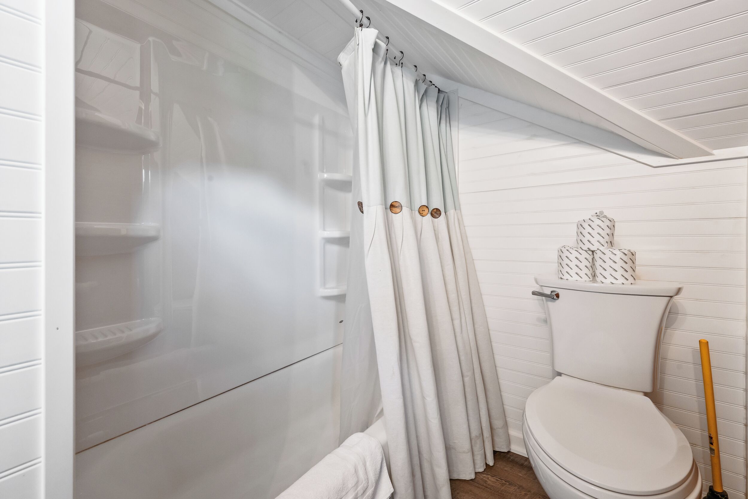 A bathroom with a shower, toilet, and a towel rack.
