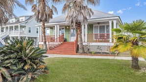 A two-story house with a porch, red railings, and a well-maintained lawn.