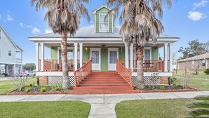 A two-story house with a green front, red steps, and a white porch.