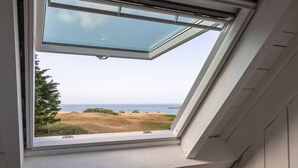 A room with a skylight overlooking a grassy field and the sea.