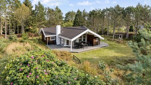 A modern house with a large deck, surrounded by dense forest. - Beautiful home in ålbæk with sauna (Ålbæk)