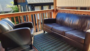 Una terraza de madera con un sofá de cuero y dos sillones de cuero.