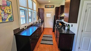 Una cocina moderna con encimera negra, armarios de madera y alfombra negra.