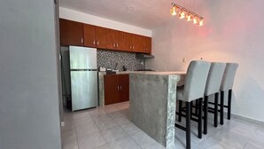 A modern kitchen with a central island, wooden cabinets, and a stainless steel refrigerator. - Jardín Departamento Privado 2 Habitaciones Cancún (Cancún)