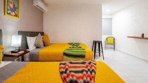 A hotel room with two beds, a desk with a lamp, a chair, and a small shelf with a statue. - Jardín Departamento Privado 2 Habitaciones Cancún (Cancún)
