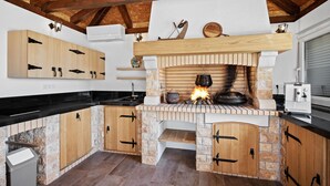 A kitchen with a wood-burning stove, stone walls, and wooden cabinets. - 1 bedroom stunning apartment in Medulin (Medulin)
