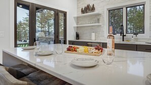 A modern kitchen with a marble countertop, a wine bottle, and a fruit platter.