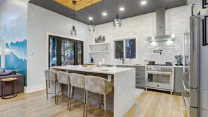 A modern kitchen with a marble island, stainless steel appliances, and pendant lighting.