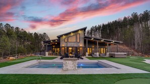 A modern house with a swimming pool, outdoor seating, and a well-maintained lawn.