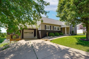 A modern two-story house with a garage, a well-maintained lawn, and mature trees.