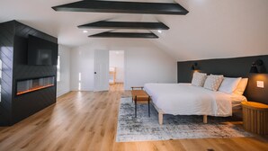 Ein modernes Schlafzimmer mit einem großen Bett, einem eingebauten Kamin und Holzboden.