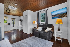 A living room with a sofa, two lamps, a TV, and a view of a mountainous landscape. - Romantic Golden Valley Cottage | View of Amish Countryside + Walk to Amish Eats (Sugarcreek)