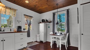 A kitchen with white cabinets, a wooden countertop, a dining table with chairs, and a window with curtains. - Romantic Golden Valley Cottage | View of Amish Countryside + Walk to Amish Eats (Sugarcreek)