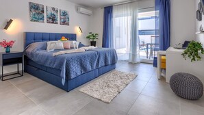 A modern bedroom with a large bed, bedside tables, a desk, and a balcony view. - Blue Rose by Interhome (Pula/Vodnjan)