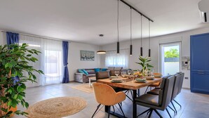 A modern living room with a sofa, dining table, chairs, and a large plant. - Blue Rose by Interhome (Pula/Vodnjan)