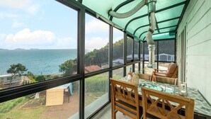 Habitación con un ventanal grande que da a un cuerpo de agua y vistas a casas. Hay una mesa con sillas y un calentador.
