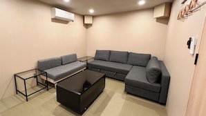 Una sala moderna con un sofá seccional gris, una mesa de centro de vidrio y un mueble de televisión negro.