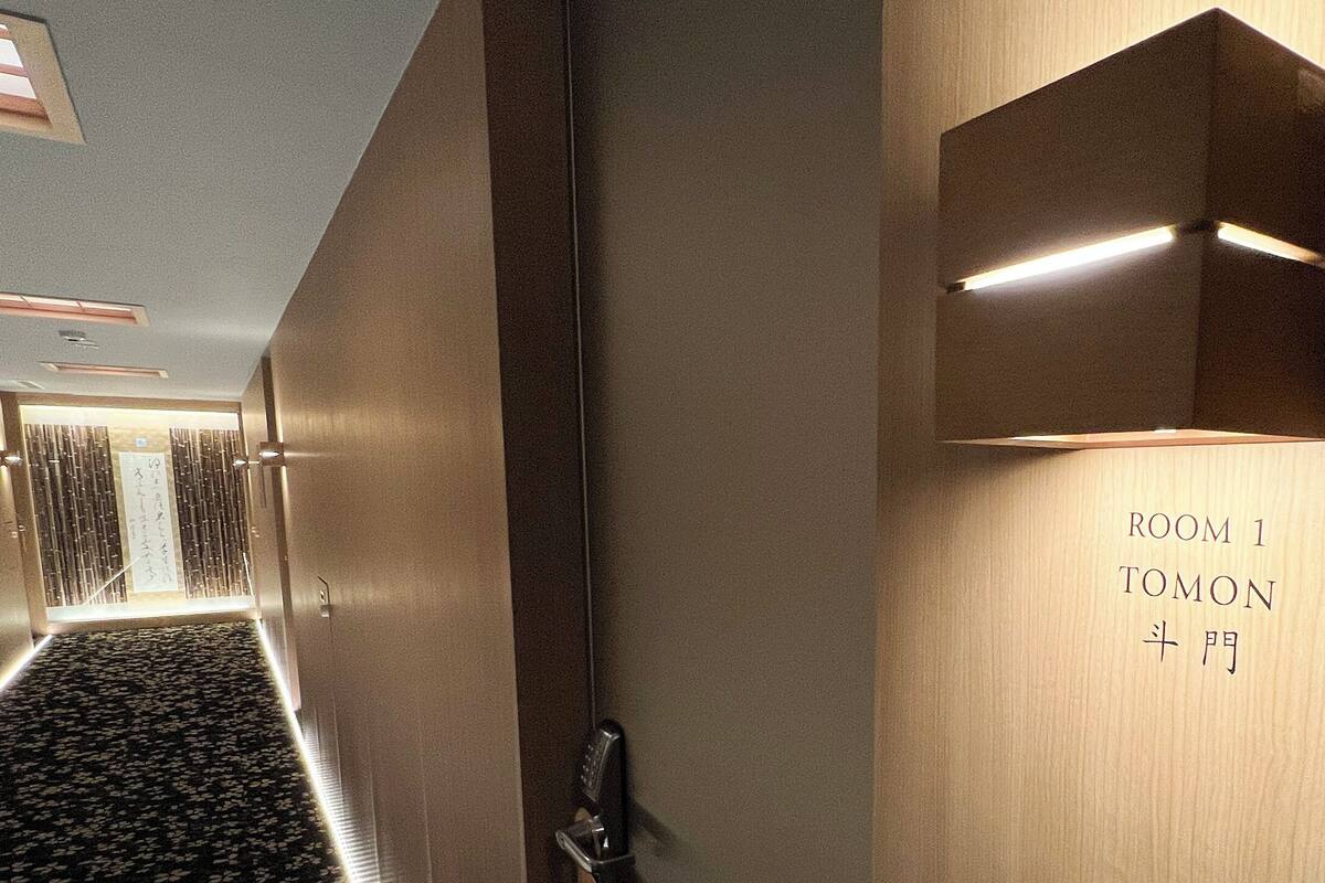 Pasillo de hotel con diseño moderno, mostrando un cartel para la habitación 1 Tomon.