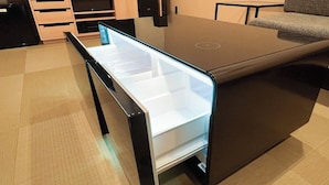 Una cocina moderna con refrigerador empotrado, un armario de madera y un sofá gris.