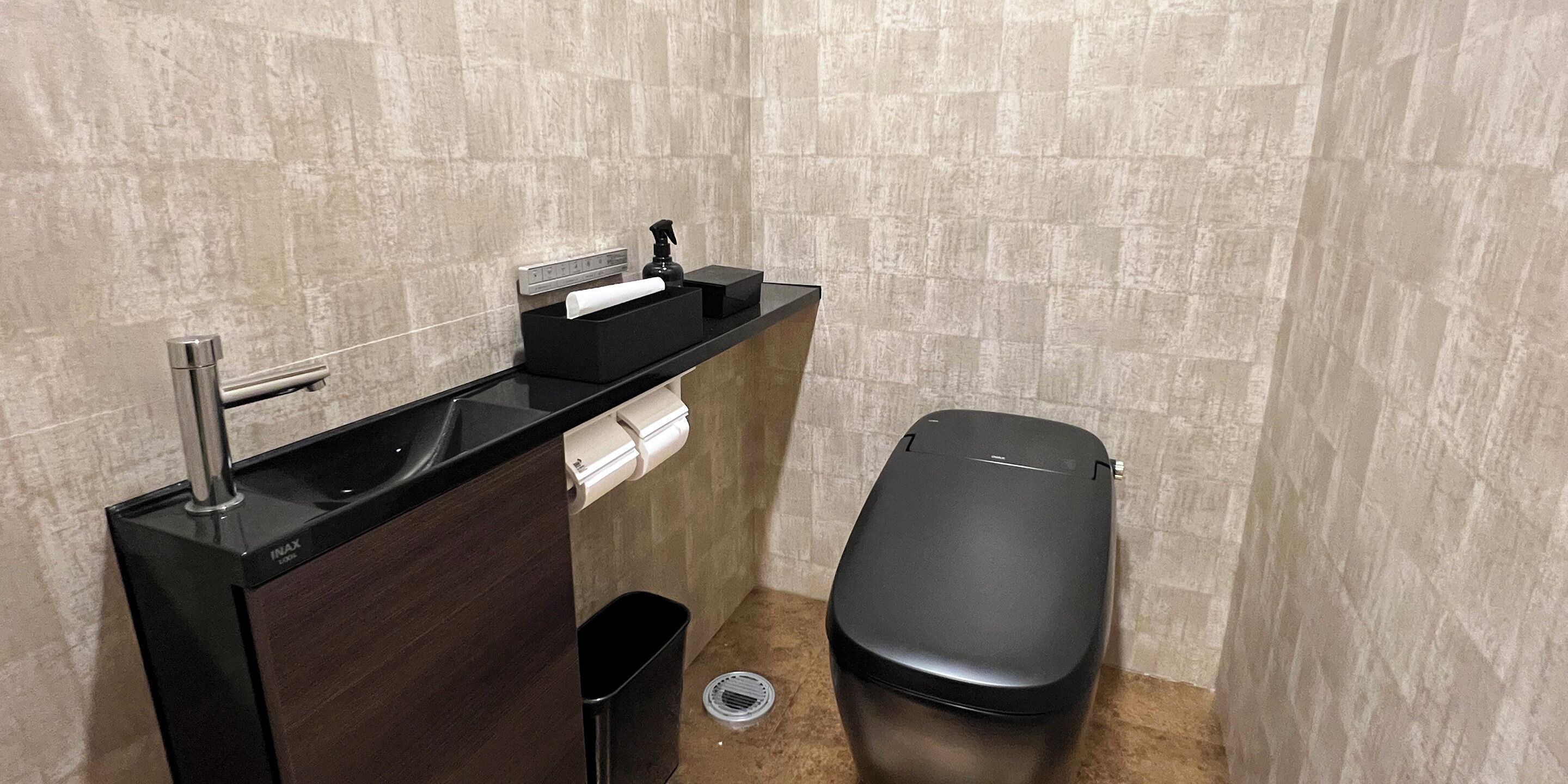 Un baño con un lavamanos negro, un inodoro y un cubo de basura.