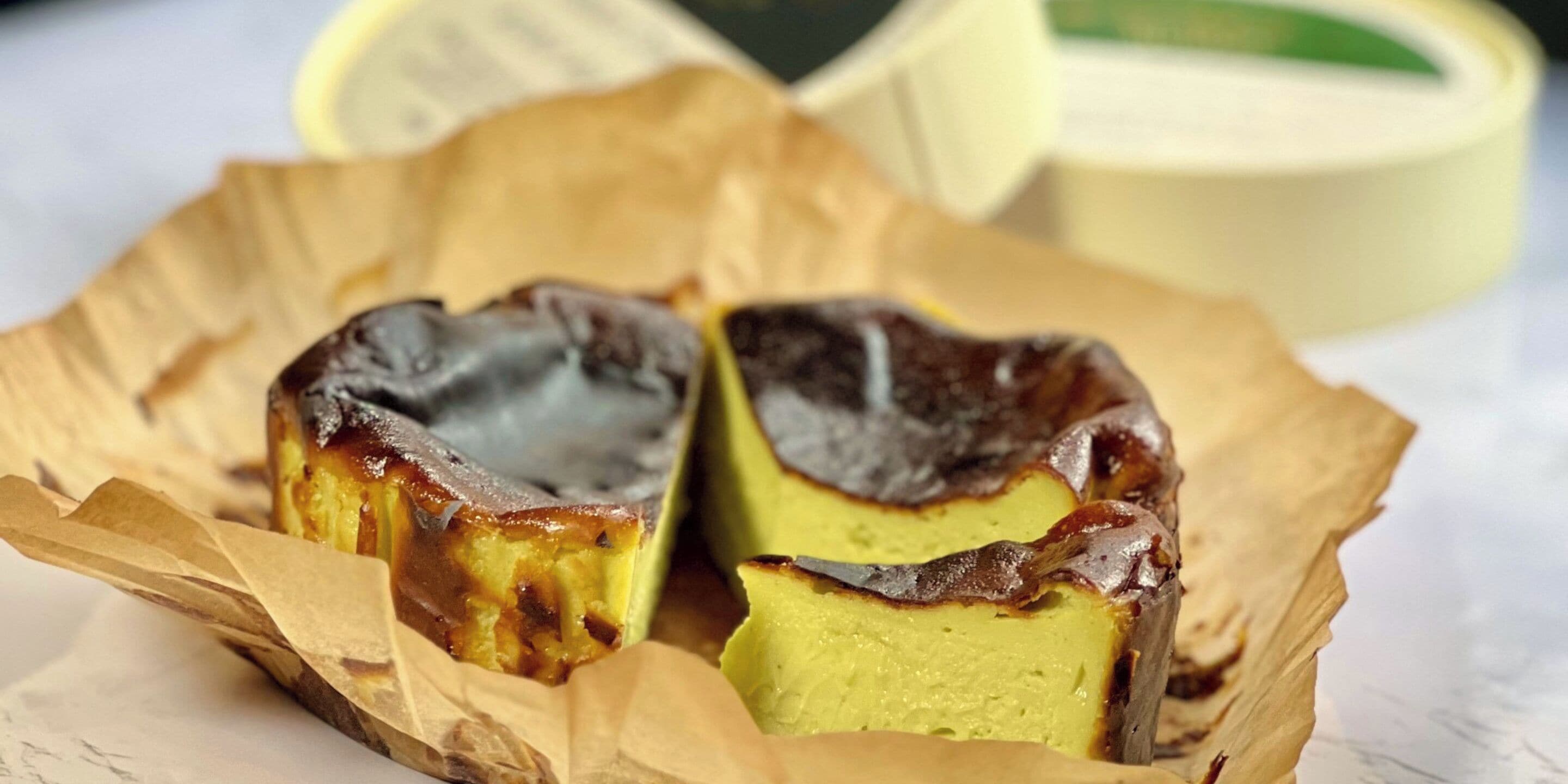 A pastry with a golden-brown top, possibly a custard or cream-based dessert, in a paper-lined container.