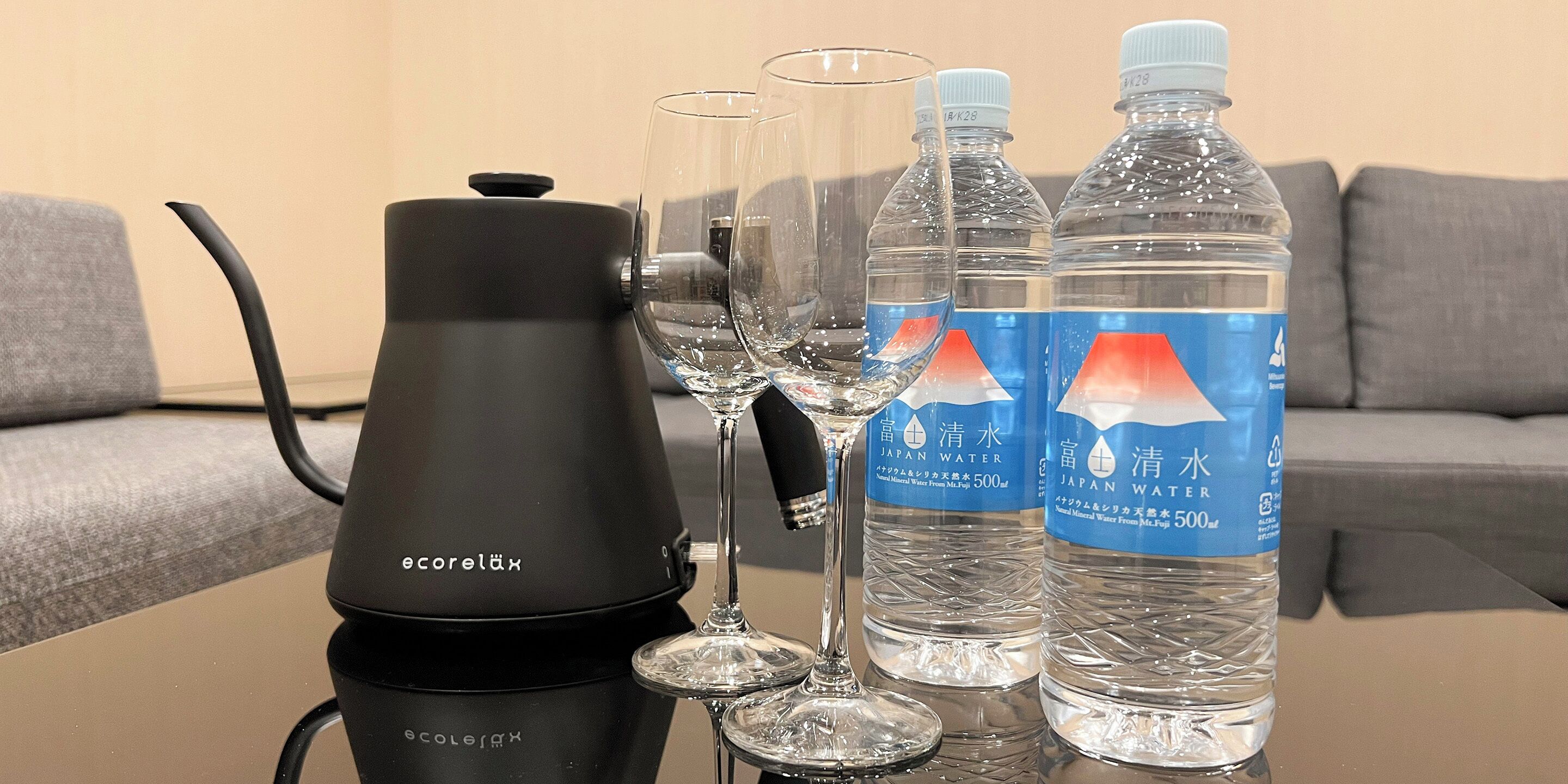 A water purifier, two glasses, and two bottles of water on a table.