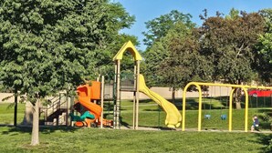 Une aire de jeux avec un toboggan et des balançoires.