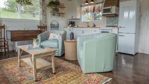 Una cocina acogedora con zona de comedor, que incluye una mesa de madera rústica, un sofá verde claro y una alfombra estampada.