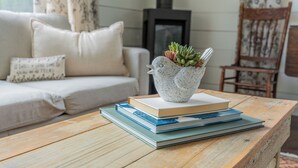 Una mesa de madera con una pila de libros y una maceta decorativa con suculentas.