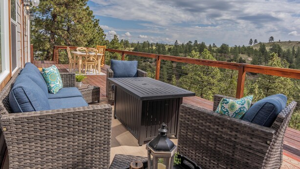 Una terraza con mobiliario de mimbre, una mesa y un farol.