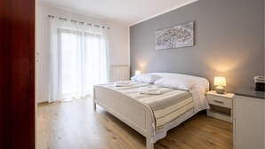 A bedroom with a bed, bedside tables, a lamp, a painting on the wall, and a window with curtains. - Nice apartment in Bresca with WiFi (Bresca)