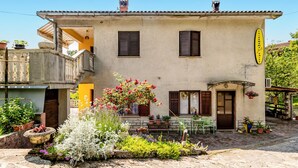 A traditional building with a balcony, a flower garden, and a sign indicating a salon. - Nice apartment in Bresca with WiFi (Bresca)