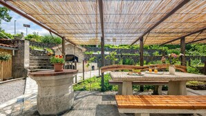 An outdoor patio with a stone bench, a table with a basket, and a potted plant. - Nice apartment in Bresca with WiFi (Bresca)